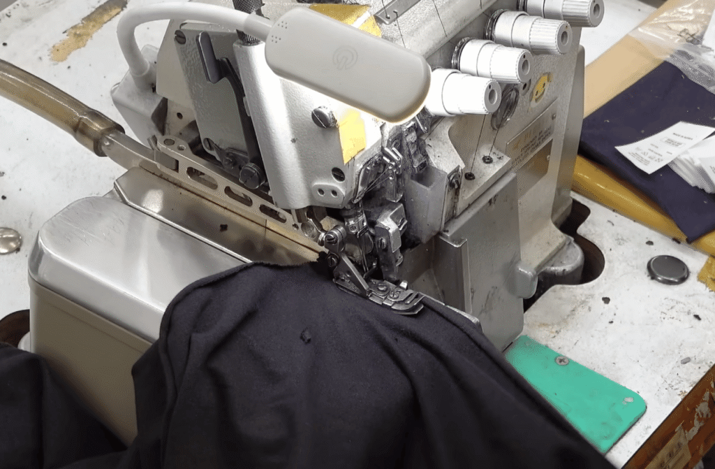 Overlocking machine securing raw fabric edges